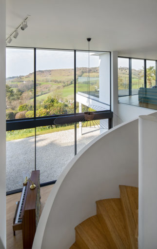 Staircase to first floor living area with curtain walling in background